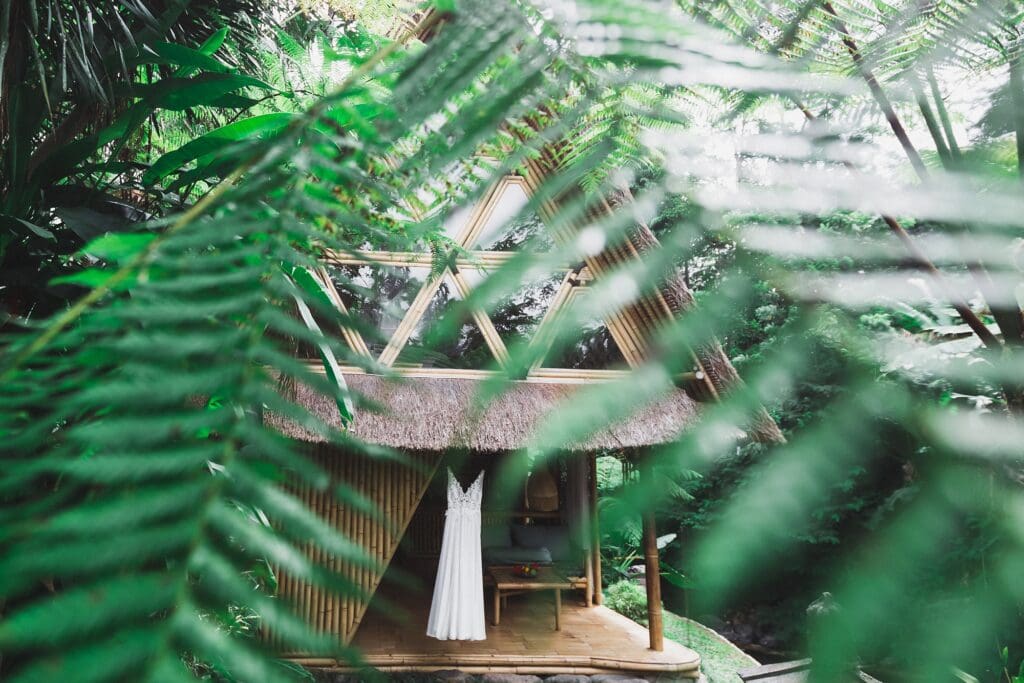 white wedding dress hanging outdoors surrounded by jungle leaves