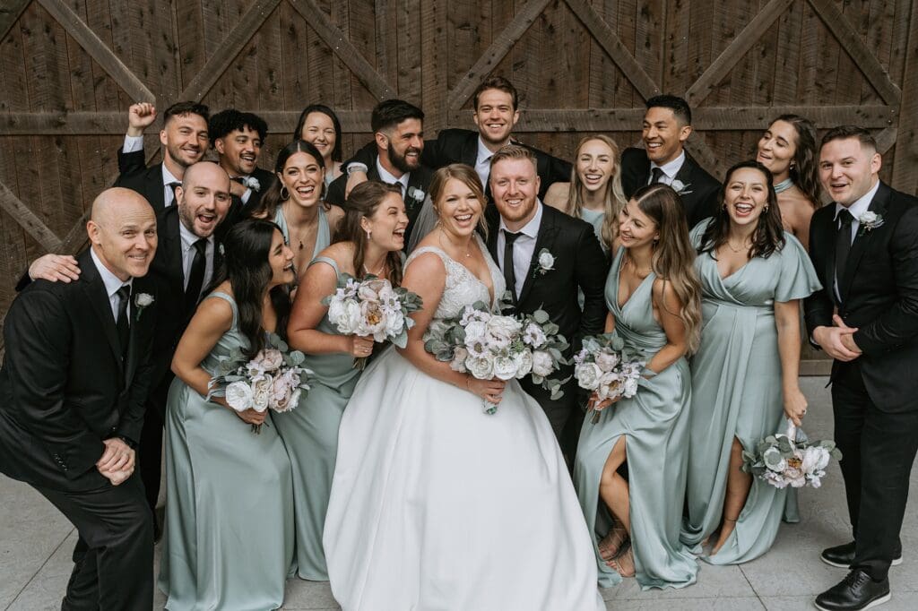 Wedding party enjoying the wedding with a wood barn background.