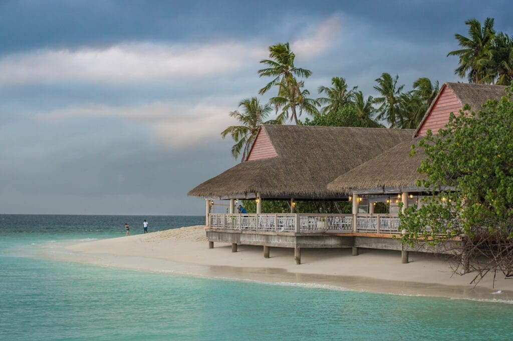 Couple walking on beach in Bali next to a beautiful Cabana.