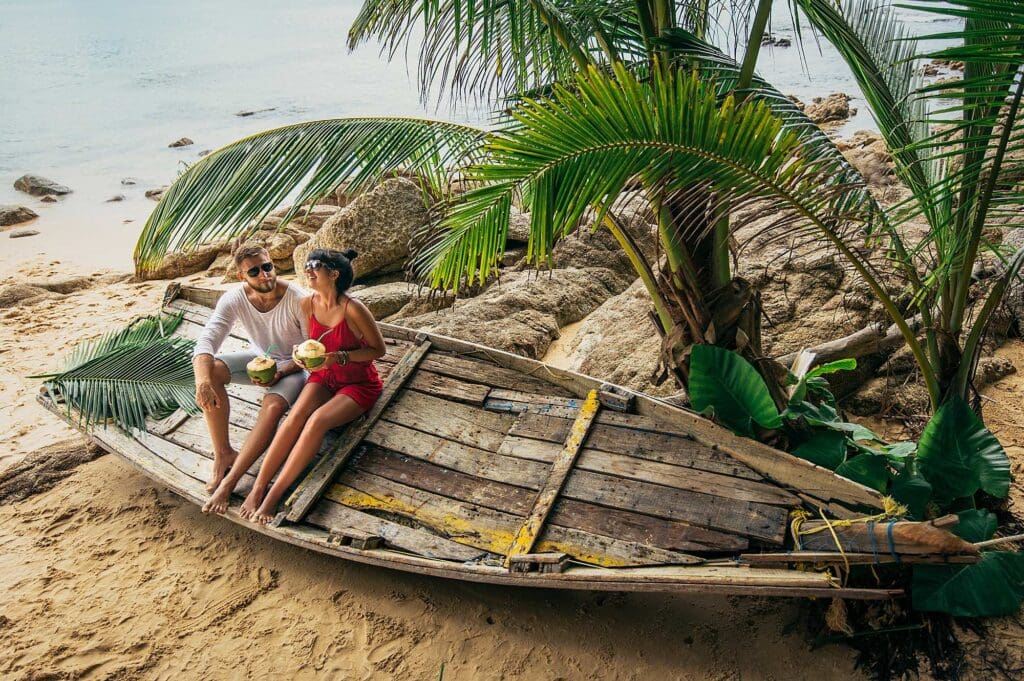couple enjoying coconut water on a bali beach sitting on boat
