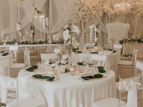 The Crystal Ballroom with white table linen decorated with china and crystal glasses. Florals in creams and white, and crystal chandeliers for dramatic lighting.