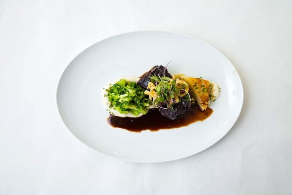 Barrington's served a white dinner plate with beef and vegetables sides in a brown sauce.
