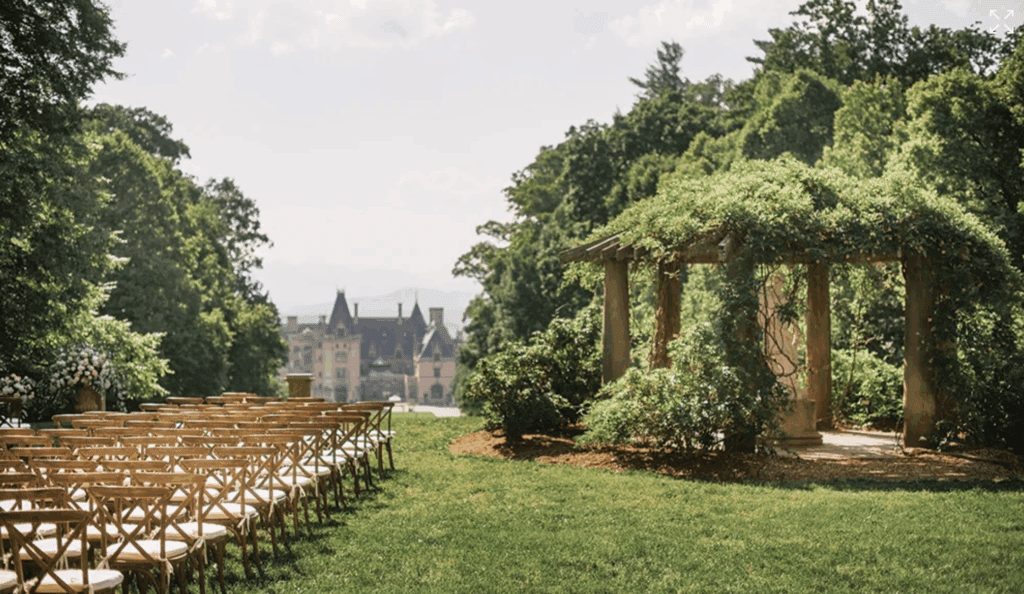 Biltmore wedding ceremony with chair lined up on the lawn and a gazebo with large columns and ivy overgrown. In the Background you can see the Biltmore Estate.