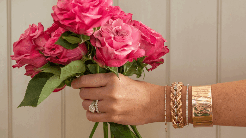 Someone holding pink roses with gold bracelets in charleston