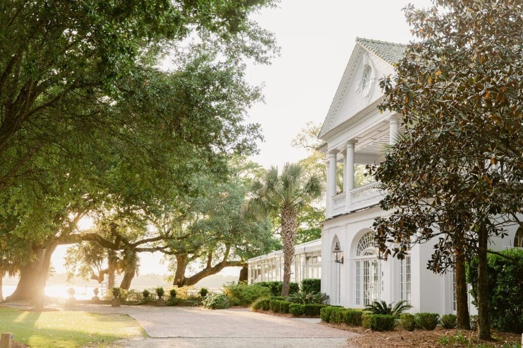 sunset behind large trees at a large white wedding venue in charleston