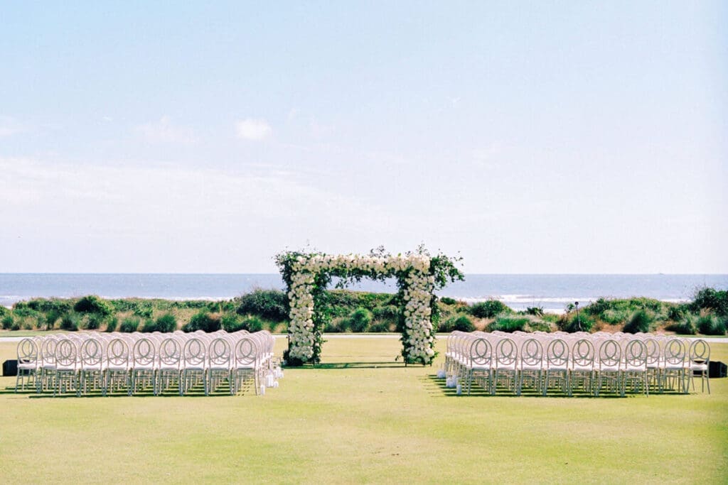 wedding ceremony setup with floral arch near ocean