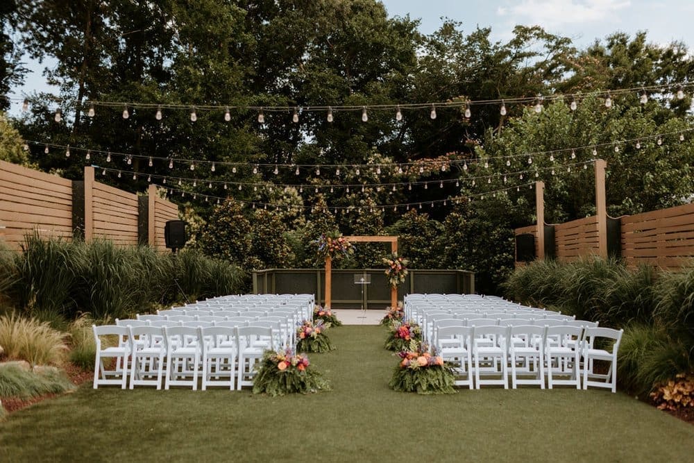 The Ruth Wedding Venue has lush gardens with string lights and a casual setting on the lawn with with chairs and florals adorning the walkways.
