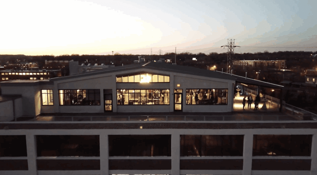 An evening view of the modern style Terrace at Cedar Hill rooftop Venue in Charlotte NC, with guest inside and outside under warm lights.