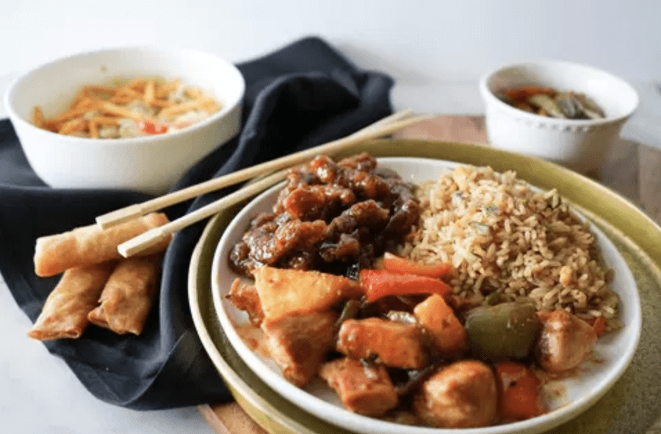 Uptown Chefs dinner served with beef and rice with side of vegetables and a soup. Chopstick placed on the side of plate and black cloth napkin.